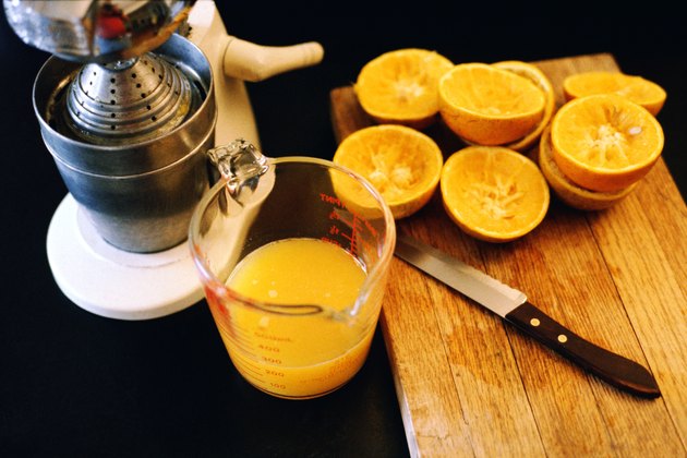 Still life of cut oranges a knife, a juicer and fresh orange juice.