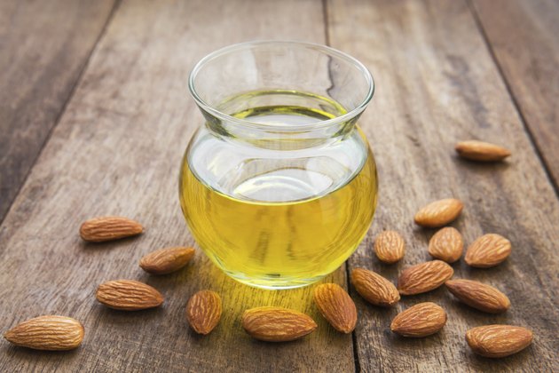 Almond oil in glass bottle and almonds