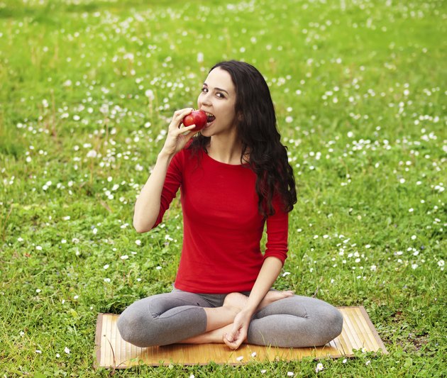 Beautiful young girl relaxing in nature andeating an apple