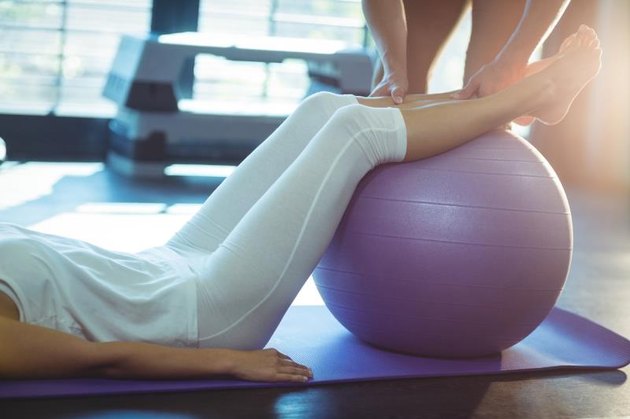 Physiotherapist assisting a patient with exercise ball in clinic