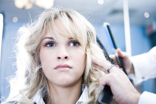 Woman getting hair straightened in salon