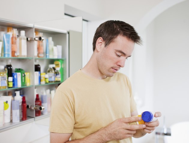 Man reading instructions on pill bottle