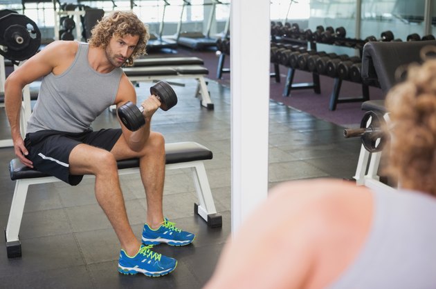 Young man exercising with dumbbell in gym