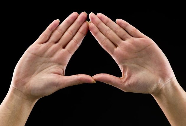 Real people, caucasian woman's hands on black background forming a triangle. In some countries this is a feminist hand sign (this picture have been shot with a Hasselblad HD3 II 31 megapixels)
