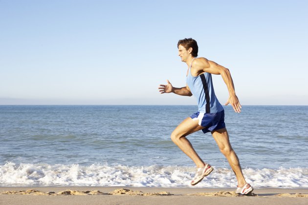 Young Man In Fitness Clothing Running Along Beach