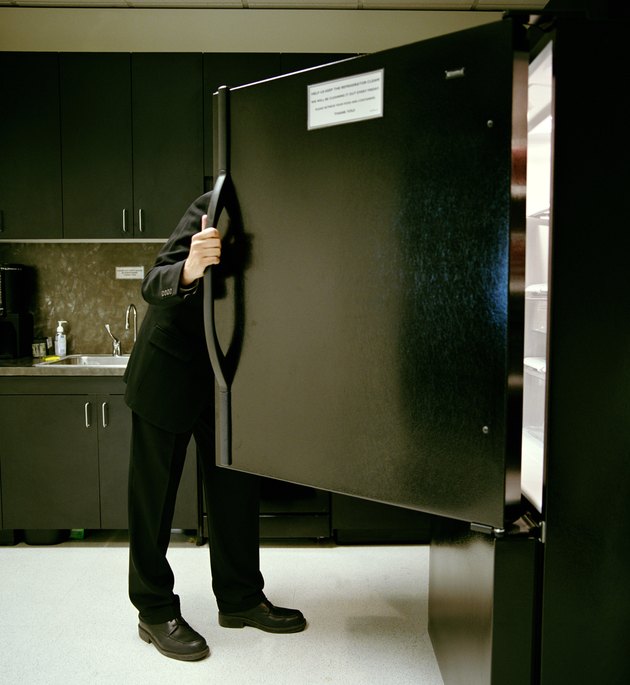 Mature businessman looking in refrigerator in office kitchen