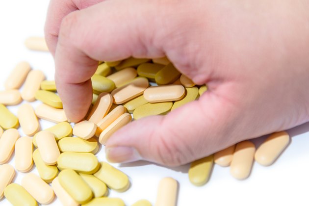 Human hand grab vitamin pills over white