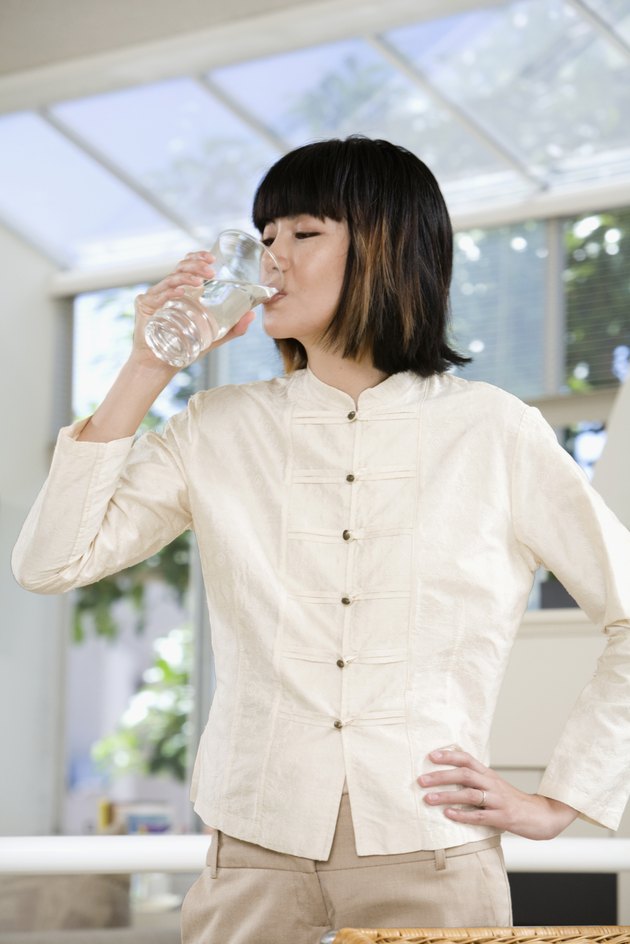Asian woman drinking glass of water