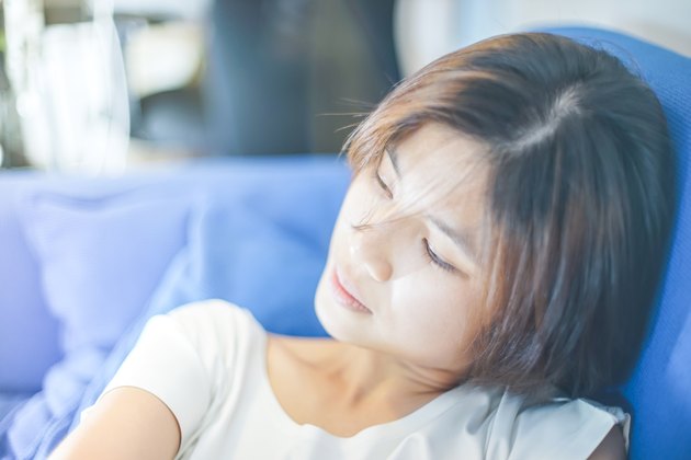 Tired Asian girl resting on a sofa.
