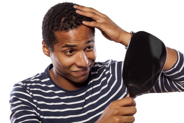 Dark-skinned young man settles himself in the mirror