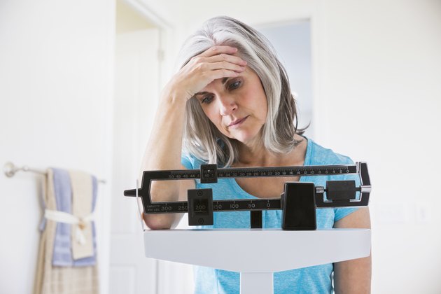 Unhappy Caucasian woman standing on weight scale