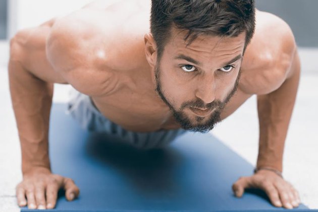 Strength and motivation. Young handsome man doing push-up at gym