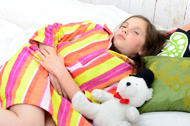 little girl in her bed has a stomachache