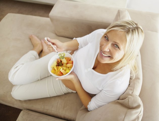 Top view of a relaxed mature woman on couch eating