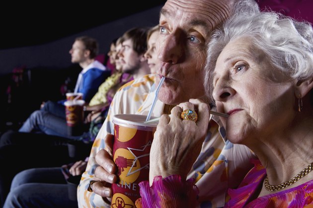Senior couple sharing drink in cinema, close-up