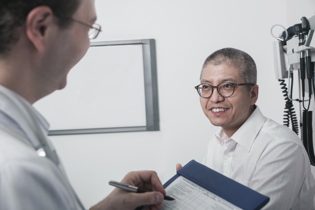Doctor writing on medical chart with a smiling patient