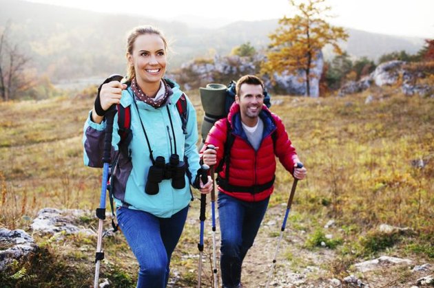 Man and woman wearing hiking gear going atop a mountain.
