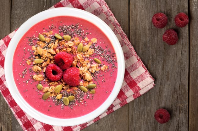 Raspberry smoothie bowl with superfoods on wood