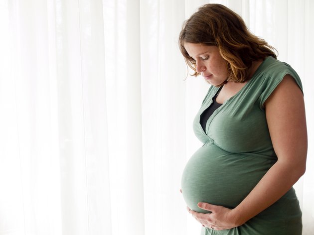 Pregnant young woman looking at her belly