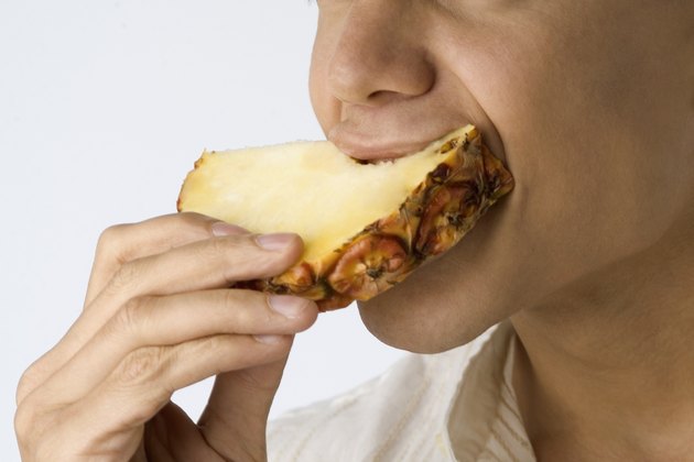 Extreme close-up of Extreme close-up of a man taking a bite pineapple