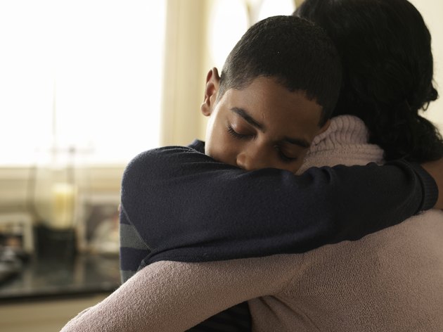Boy (12-13) hugging mother at home