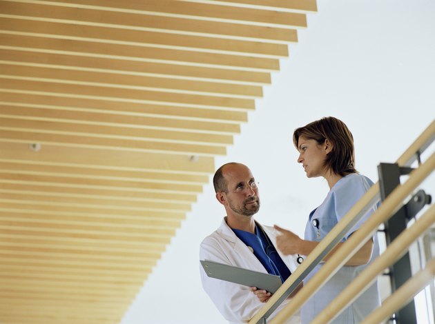 Mature male doctor and young female nurse talking by railing