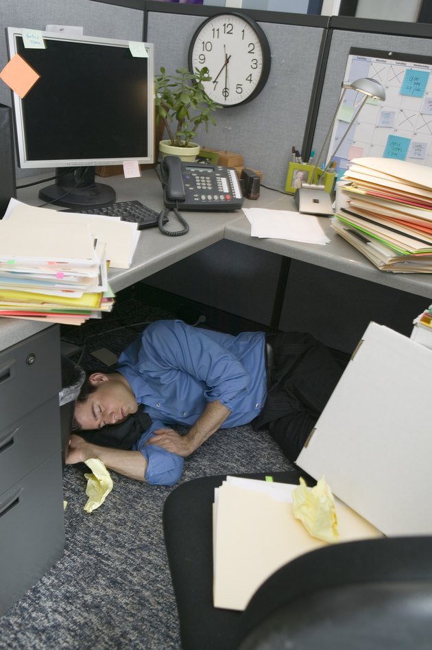 Businessman sleeping in cubicle