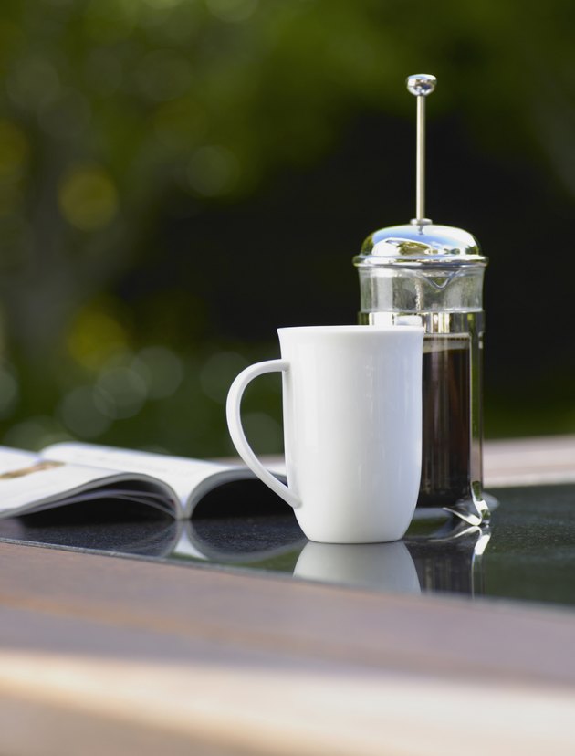 Coffee cup and plunger on table