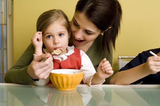 Woman feeding girl cereal