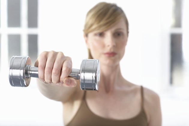 Woman holding dumb-bell, portrait, (focus on dumb-bell)
