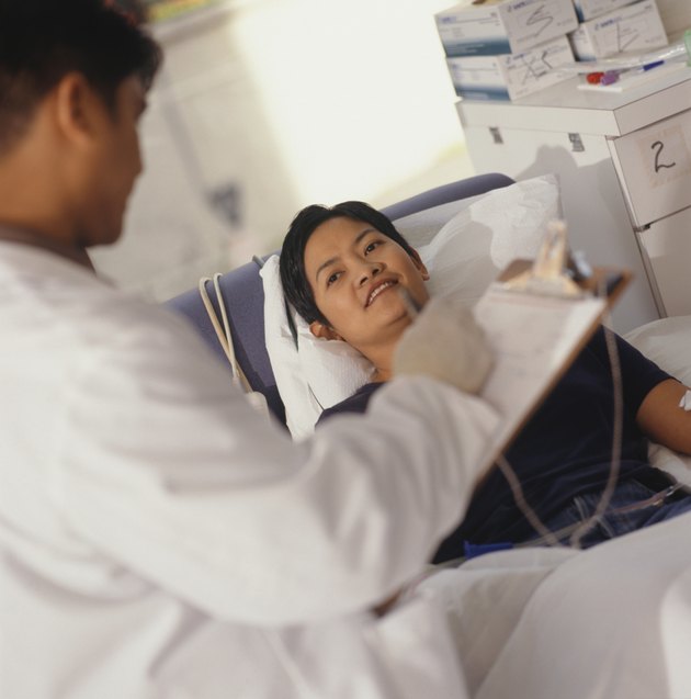 Doctor with patient in hospital, patient in bed, focus on patient