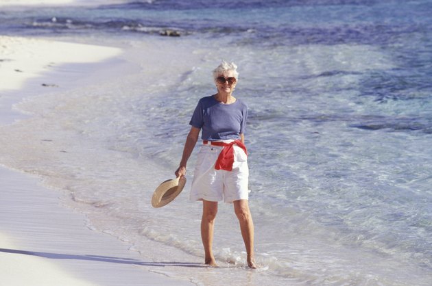 Senior woman walking barefoot on beach