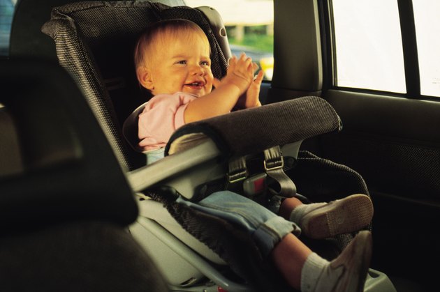 Baby sitting in a car seat and clapping hands
