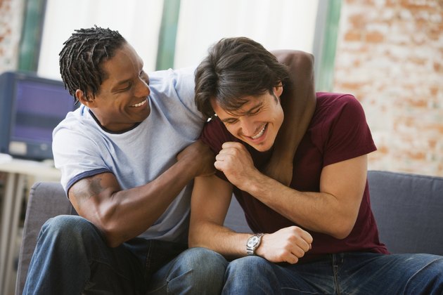 Multi-ethnic men hugging on sofa