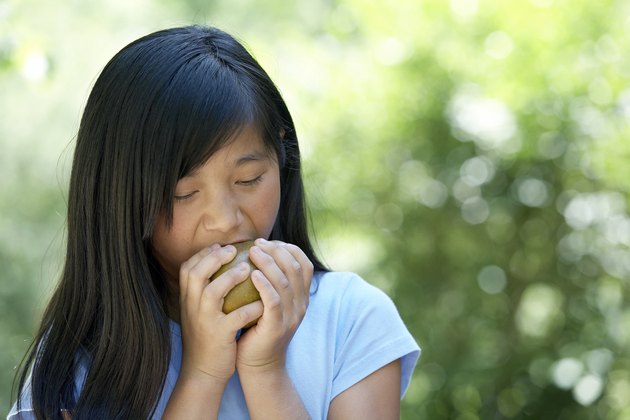 Close-up of a teenage girl eating a pear