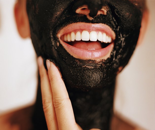 Woman with mud mask on face and neck, mouth open
