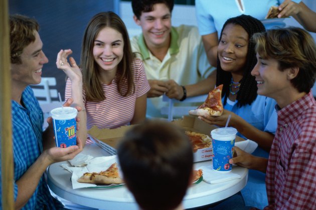High angle view of a group of teenagers eating pizza in a restaurant