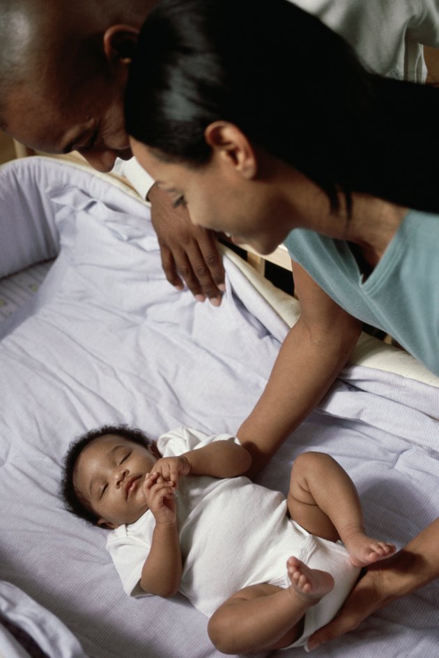 High angle view of parents looking at their baby boy sleeping in a crib