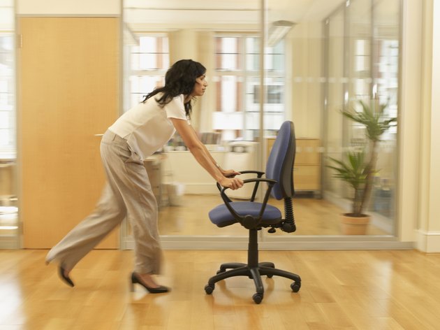 Hispanic businesswoman pushing office chair