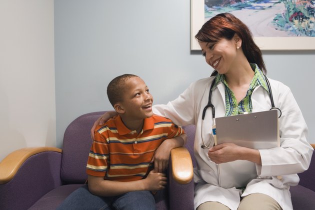 Hispanic female doctor hugging boy in waiting room