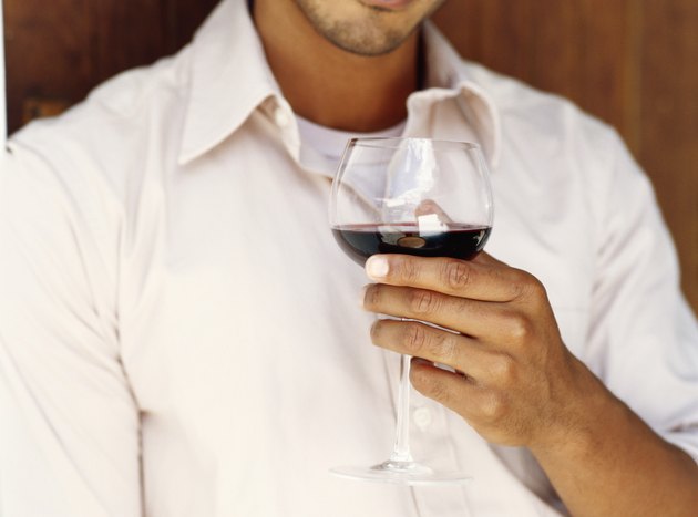 Young man drinking glass of red wine, close-up