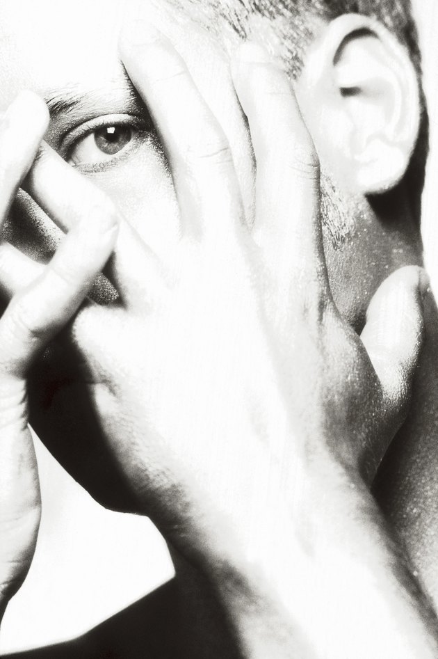Close-up of a young man covering his face with his hands