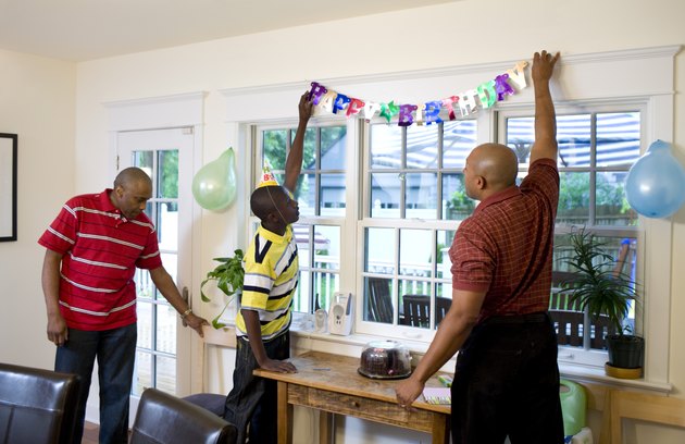 Men and boy hanging birthday decorations