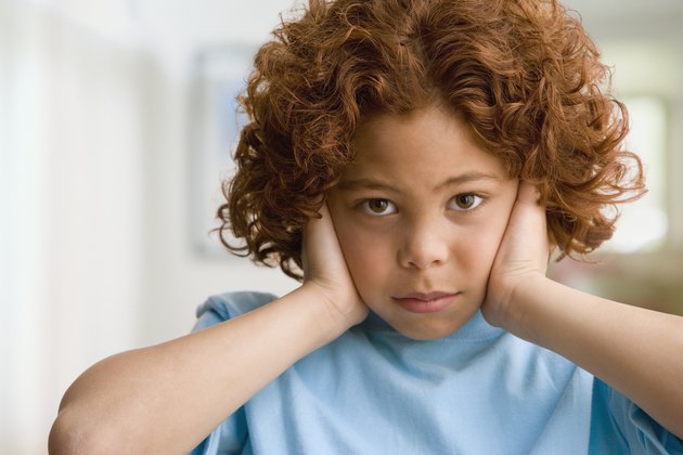 Mixed Race boy covering ears