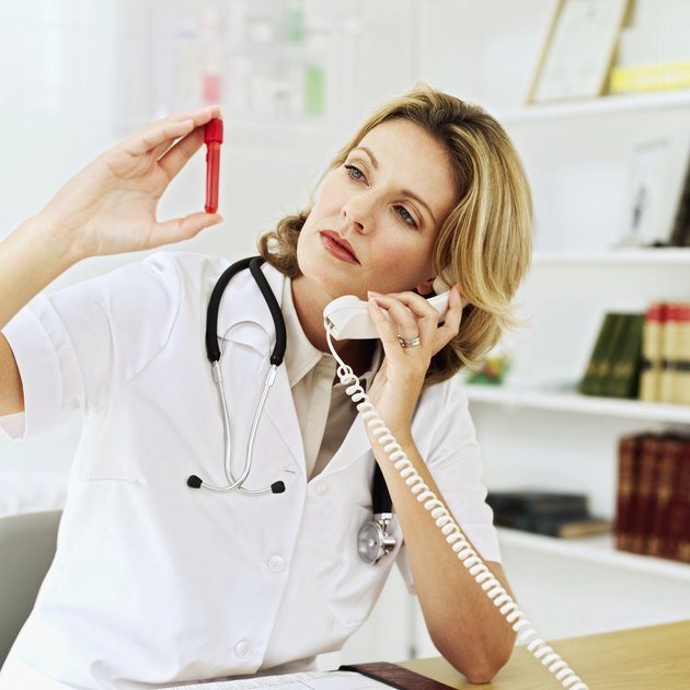 Young female medical professional holding a test tube and talking on a telephone
