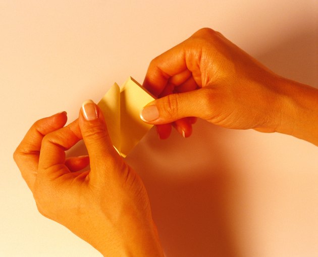 Woman's hands peeling off a post-it note.
