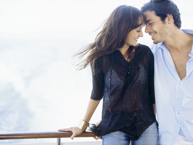 Young couple standing leaning against a railing of a boat