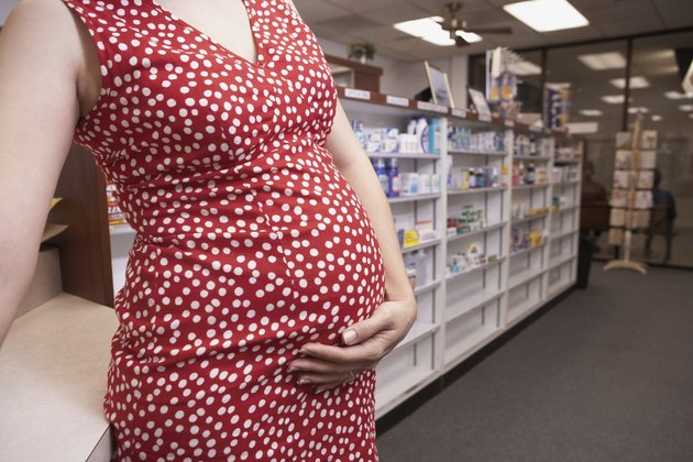 Pregnant woman holding belly in pharmacy