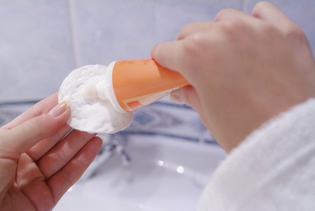 Close-up of a mid adult woman squeezing cream from a tube