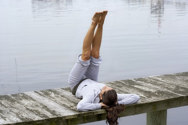 Young woman exercising on dock, rear view, close-up